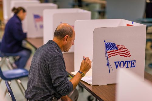 Voter at polls during presidential election, using paper ballots.