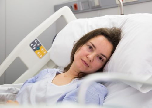 Brunette adult woman is lying fever on the bed in hospital indoor