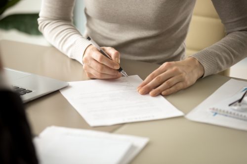 Woman signing document, focus on female hand holding pen, putting signature at official paper, subscribing name in statement with legal value, contract management.