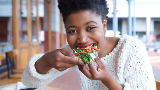 Close up portrait of an happy african american woman eating pizza