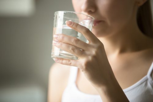 Female drinking from a glass of water.