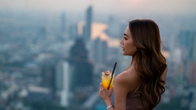 Woman drinking cocktail while waiting for meeting with friends at skyscraper.