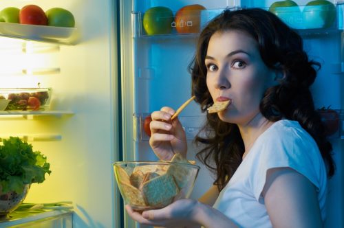 Hungry woman opens the fridge.