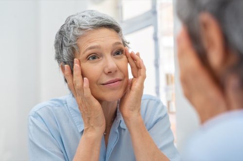 Senior woman checking her face skin and looking for blemishes.