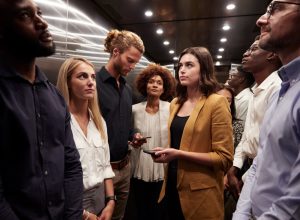 Work colleagues stand waiting together in an elevator at their office.