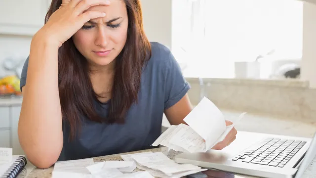 Brunette,Looking,Worried,Over,Bills,In,Kitchen.,Working,From,Home