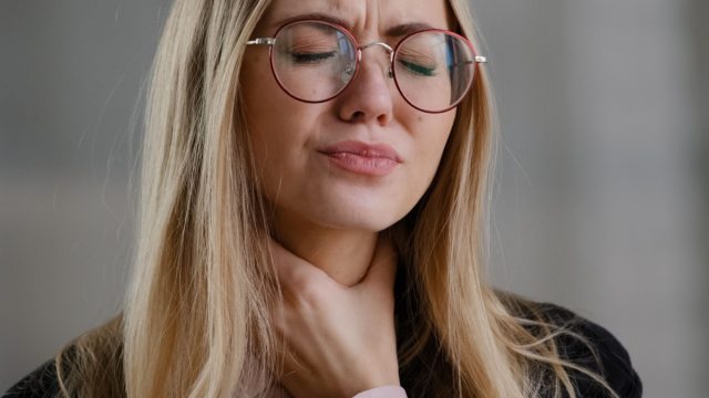 Woman touching her throat.