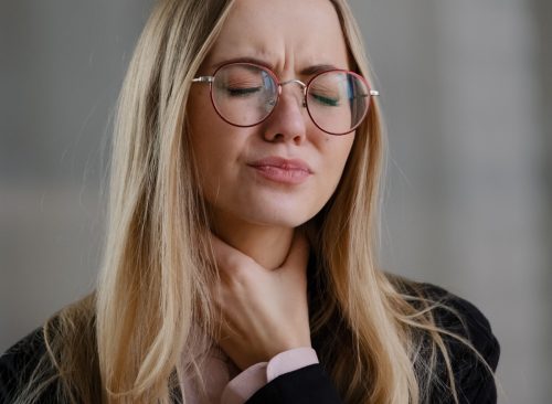 Woman touching her throat.