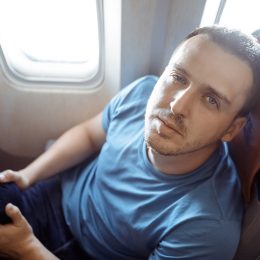 Male passenger feeling dizzy having airsickness while traveling on plane. Man looking at camera