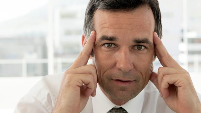 incentive for thinking first - portrait of a middle aged corporate businessman with fingers on head