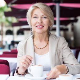 Portrait of elegant mature female who is enjoying of lunch with coffee in cafe.