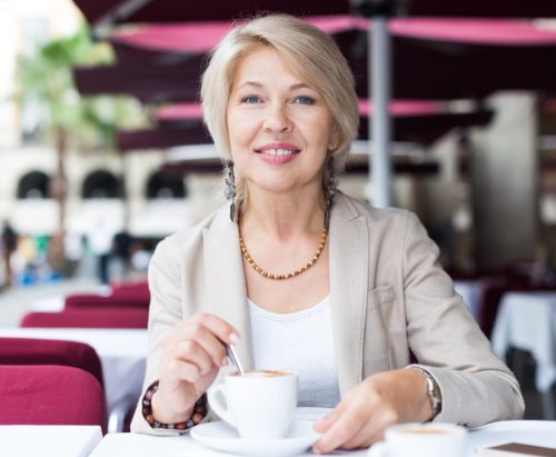 Portrait of elegant mature female who is enjoying of lunch with coffee in cafe.