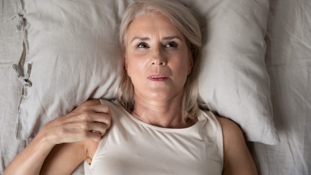 Middle aged mature woman insomniac lying awake in bed