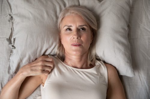 Middle aged mature woman insomniac lying awake in bed