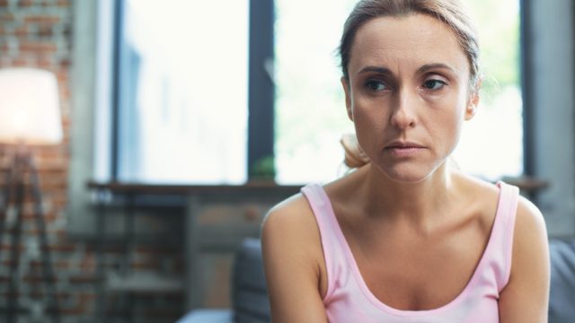 Serious mature woman looking aside and posing on blurred background.