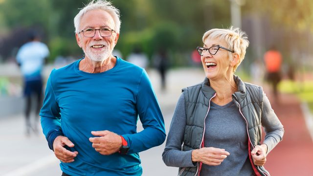 Mature,Cheerful,Active,Senior,Couple,Jogging,Together,Outdoors,Along,The,River.
