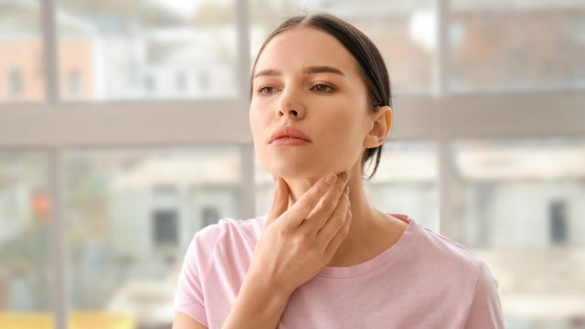 Young woman with thyroid gland problem at home