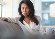 Mature woman sitting on the sofa feeling sad and alone.