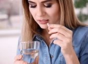 Young woman taking pill indoors.