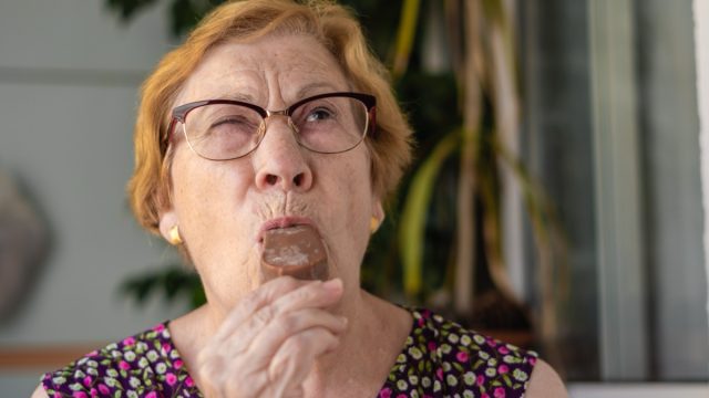 Close-up portrait, older woman enjoying a chocolate ice cream.