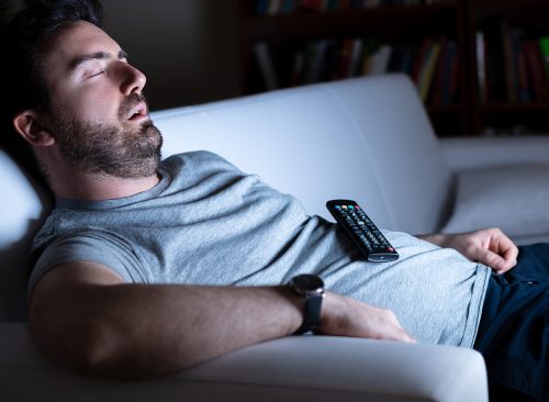 Lazy man watching television at night alone