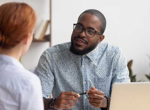 African hr manager listening to caucasian female applicant asking questions at job interview business meeting, diverse recruiter employer and seeker client talking, human resource, recruiting concept