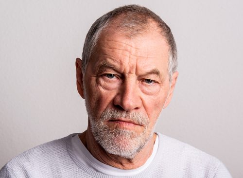 Portrait of a serious senior man in a studio, looking at camera.