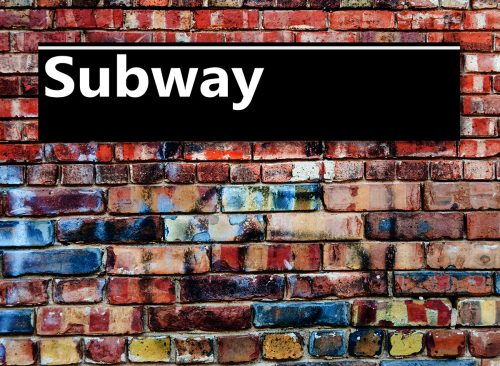 Subway or Underground sign board on a graffiti laden brick wall