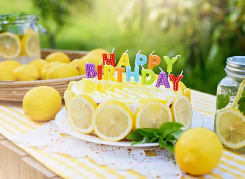 Birthday cake with happy birthday candles. Lemonade birthday party at summer park. food, celebration and festive concept. Mason jar glass of lemonade with lemons and straw.