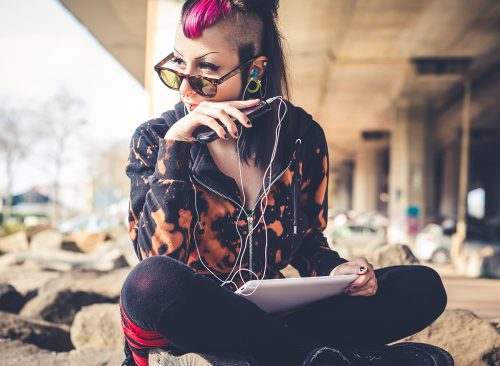 young beautiful punk dark girl using tablet in urban landscape