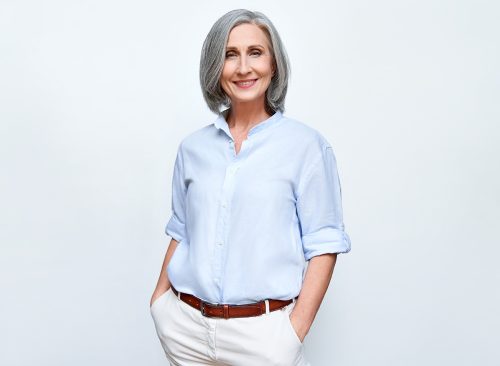 Smiling confident middle aged business woman standing isolated on white background. Old senior businesswoman, 60s grey haired lady professional female manager, leader looking at camera, copy space.