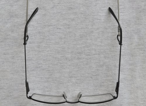 Black reading glasses grey eyeglasses straps retainers hanging readers croakies gray t-shirt vertical copy space background close vision presbyopia eyestrain eyesight farsightedness hyperopia concept