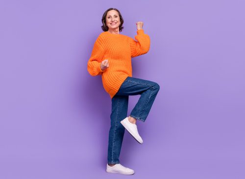 Full size profile side photo of cheerful senior woman celebrate victory fists hands isolated over purple color background