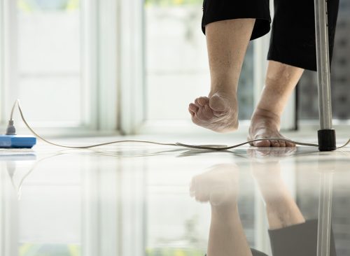 Electrical cord or socket cluttered on the floor,feet of senior woman stepping over obstacles,elderly people walking with difficulty in home,concept of danger,injury and risk of accident in falling