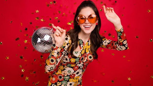 Portrait of attractive trendy girl holding disco ball dancing old school having fun isolated over bright red color background