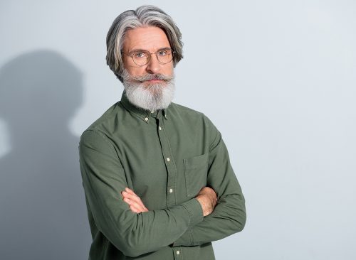 Portrait of attractive content grey-haired man expert agent copy space folded arms isolated over gray pastel color background