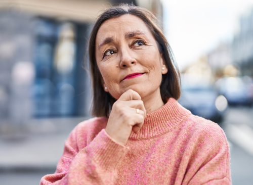 Middle age woman standing with doubt expression at street