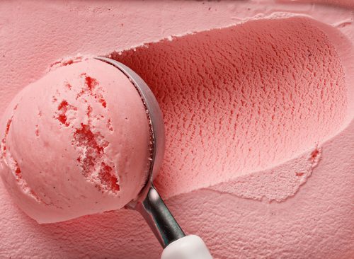 pink strawberry ice cream ball in a spoon, top view