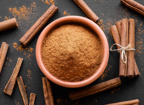 Cinnamon sticks and cinnamon powder on dark rustic background, healthy spice, (Cinnamomum)