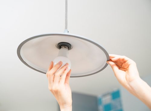 Lifestyle image of a young woman exchanging light bulbs