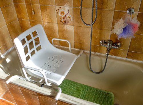 Swivel chair positioned on the bathtub for use by disabled individuals and elderly people with difficulty in walking to enter the bathtub