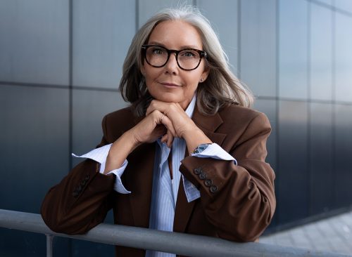 portrait of a well-groomed slender senior business woman with gray hair dressed in an elegant brown jacket over a shirt