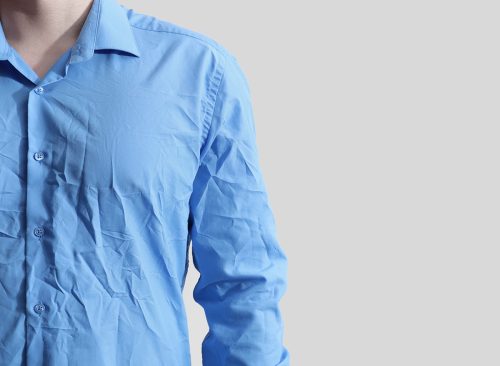 Man wearing creased shirt on light background, closeup. Space for text