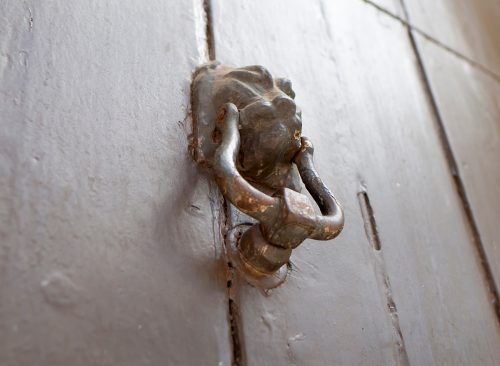 An old wooden door with an iron handle in the shape of a lion.Bottom view and blurred background.