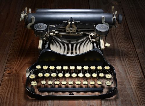 Overhead shot of an antique typewriter on a rustic wood table.