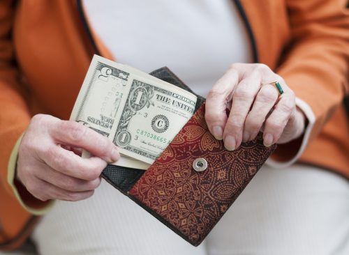 Senior women looks in her purse with US dollar bills.
