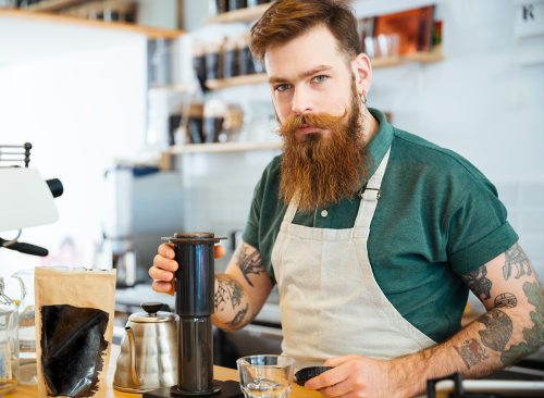 Handsome young man preparing coffee in coffee shop