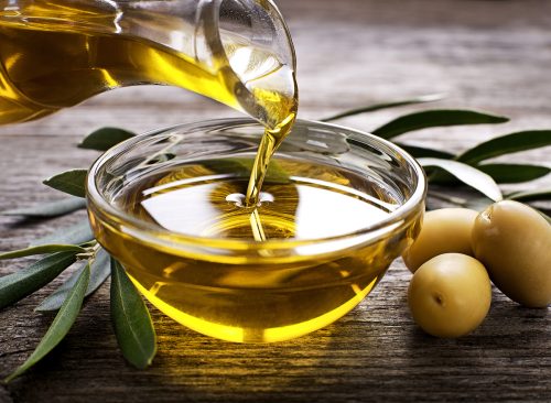 Bottle pouring virgin olive oil in a bowl close up