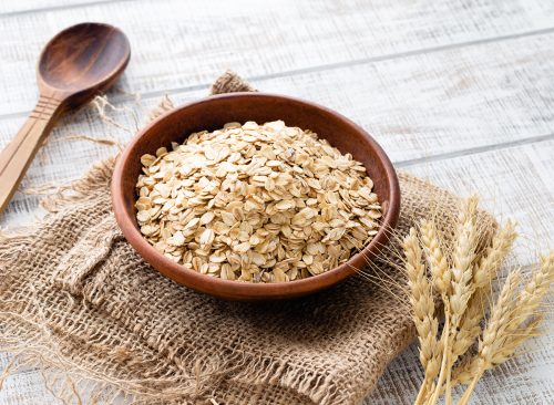 Rolled oats, healthy breakfast cereal oat flakes in bowl on wooden table