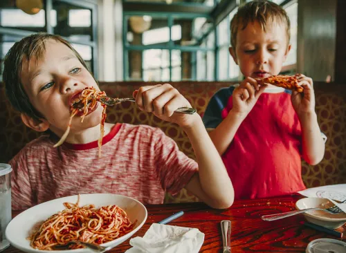 children eat unhealthy food in a cafe. kids enjoy pasta and pizza